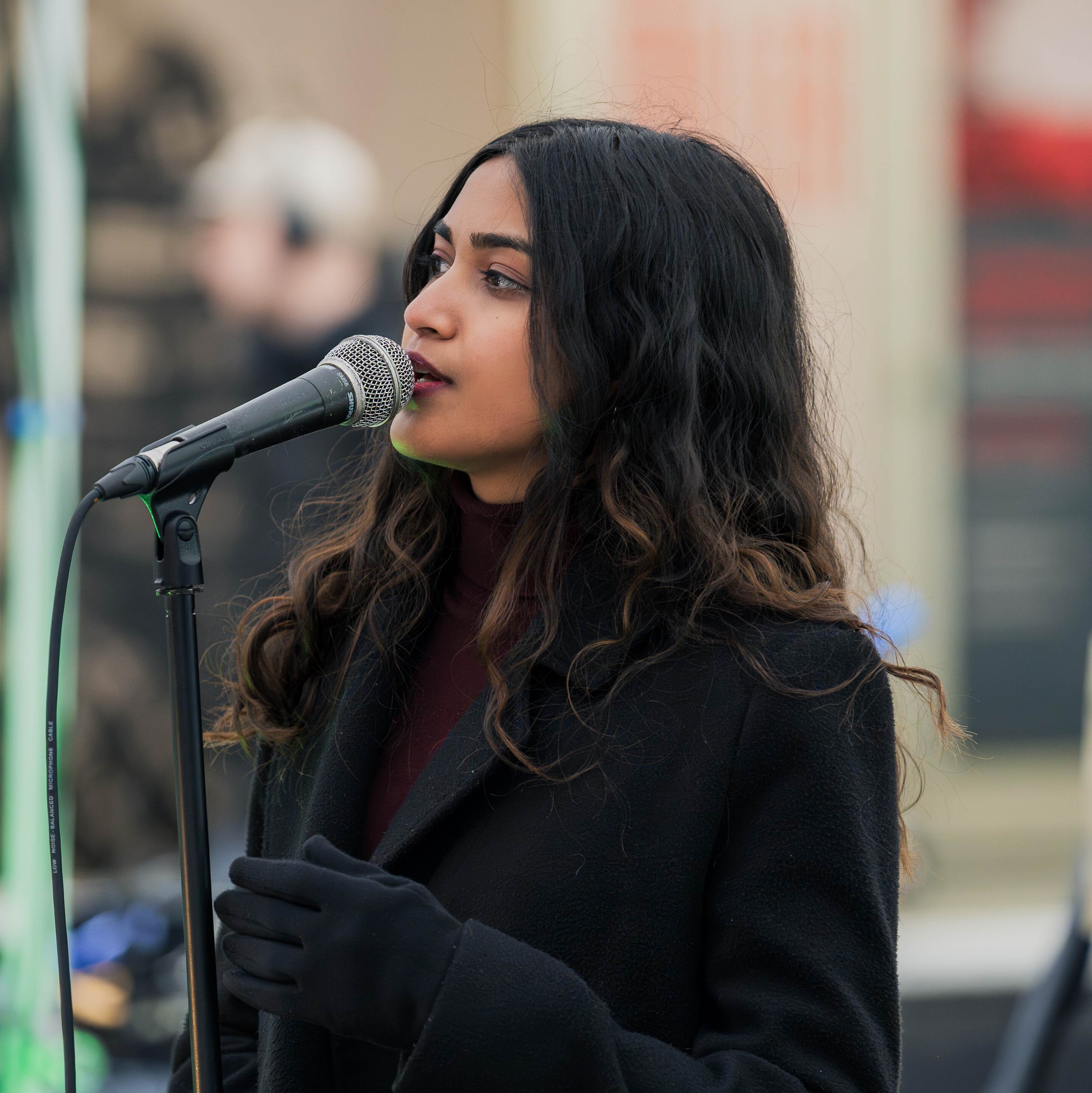 Preethi in front of a microphone, singing.